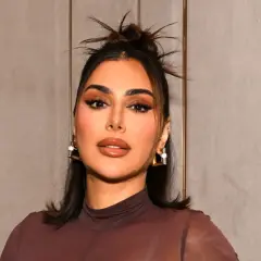 Kobieta z perfekcyjnym makijażem, jak po użyciu Huda Beauty Easy Blur, z błyszczącymi ustami i wyrazistymi oczami.