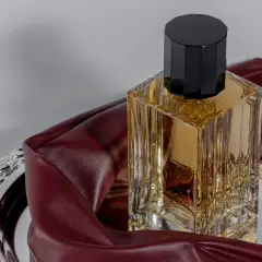 Eleganckie perfumy z lat 2000. w szklanej butelce z czarną nakrętką, na ozdobnej tacy z bordową skórką.