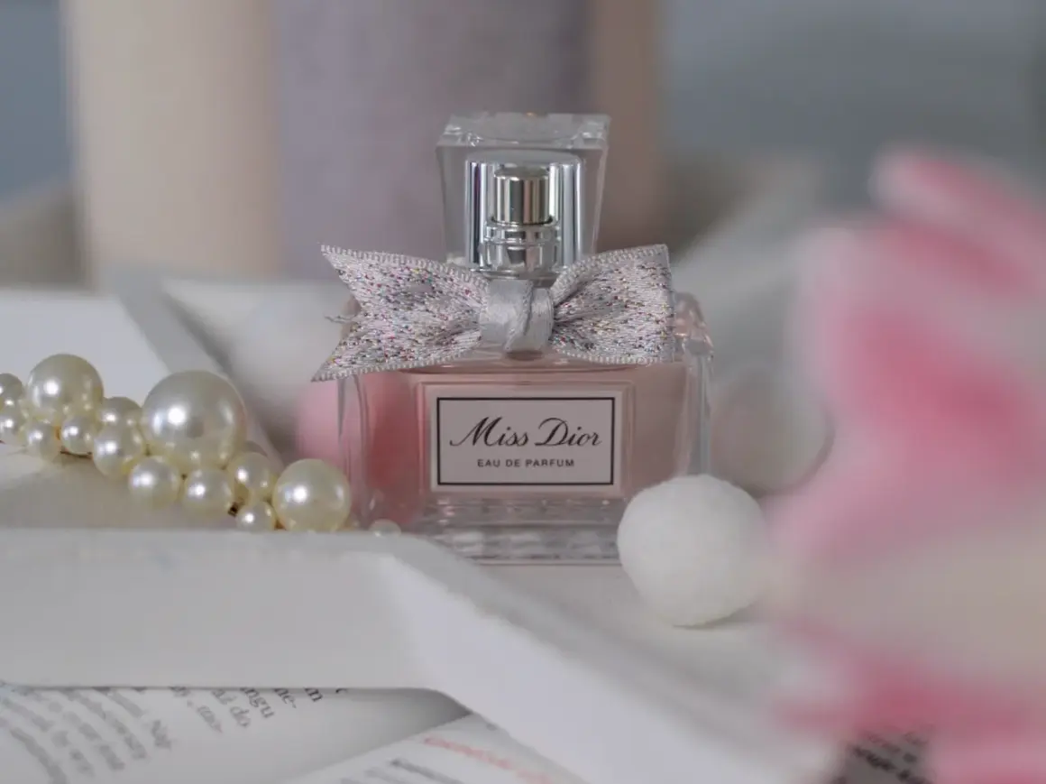 Elegancka butelka Miss Dior 100ml z kokardką, otoczona perłami i delikatnymi, białymi kulkami.